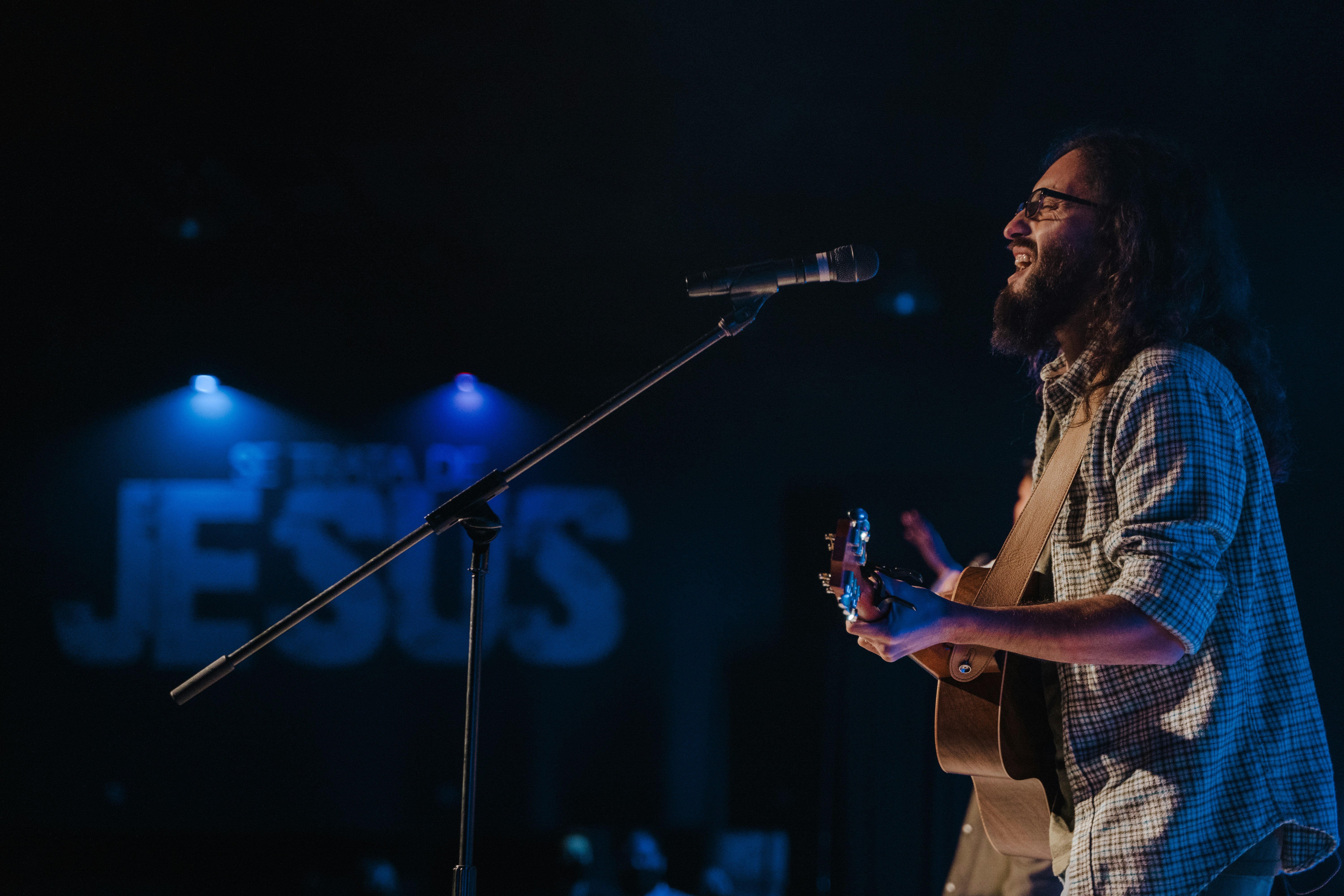 man in black and white plaid button up shirt singing on stage